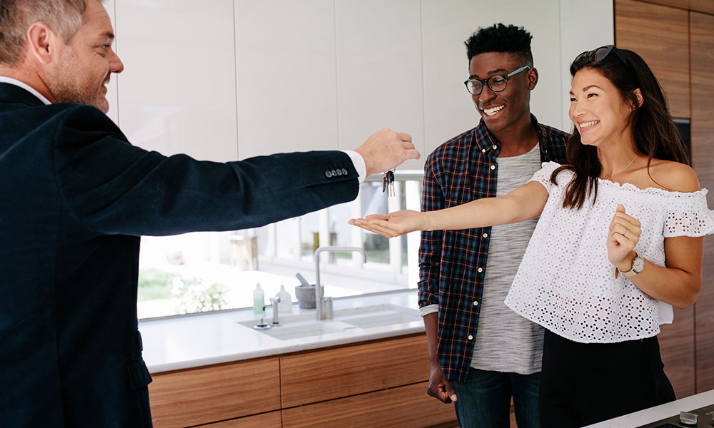 couple getting keys to their new home from their realtor