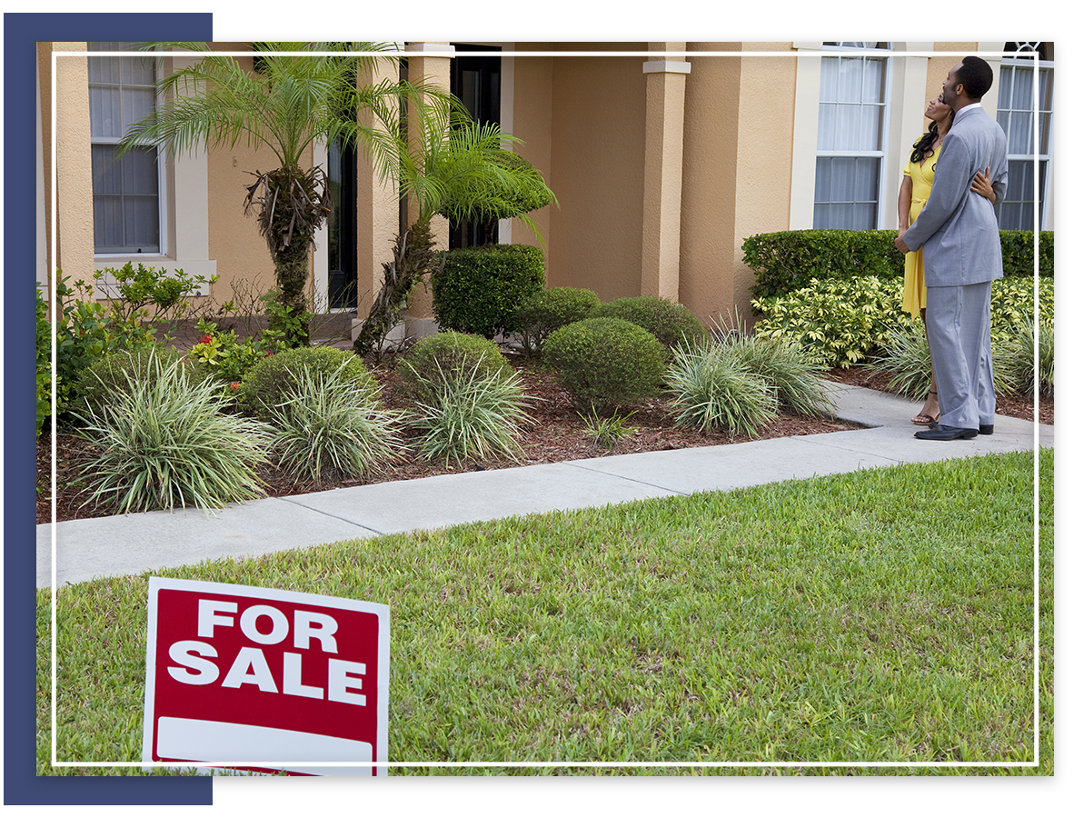 couple looking at home with for sale sign in front yard