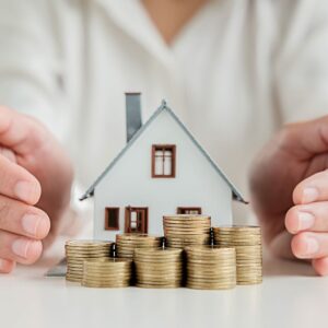 A miniature house with stacks of coins in front of it