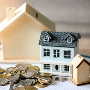 Miniature house models next to a pile of coins