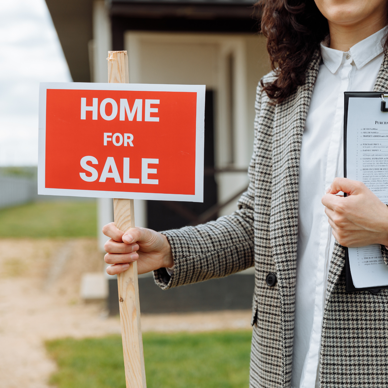 A real estate agent holding a "home for sale" sign