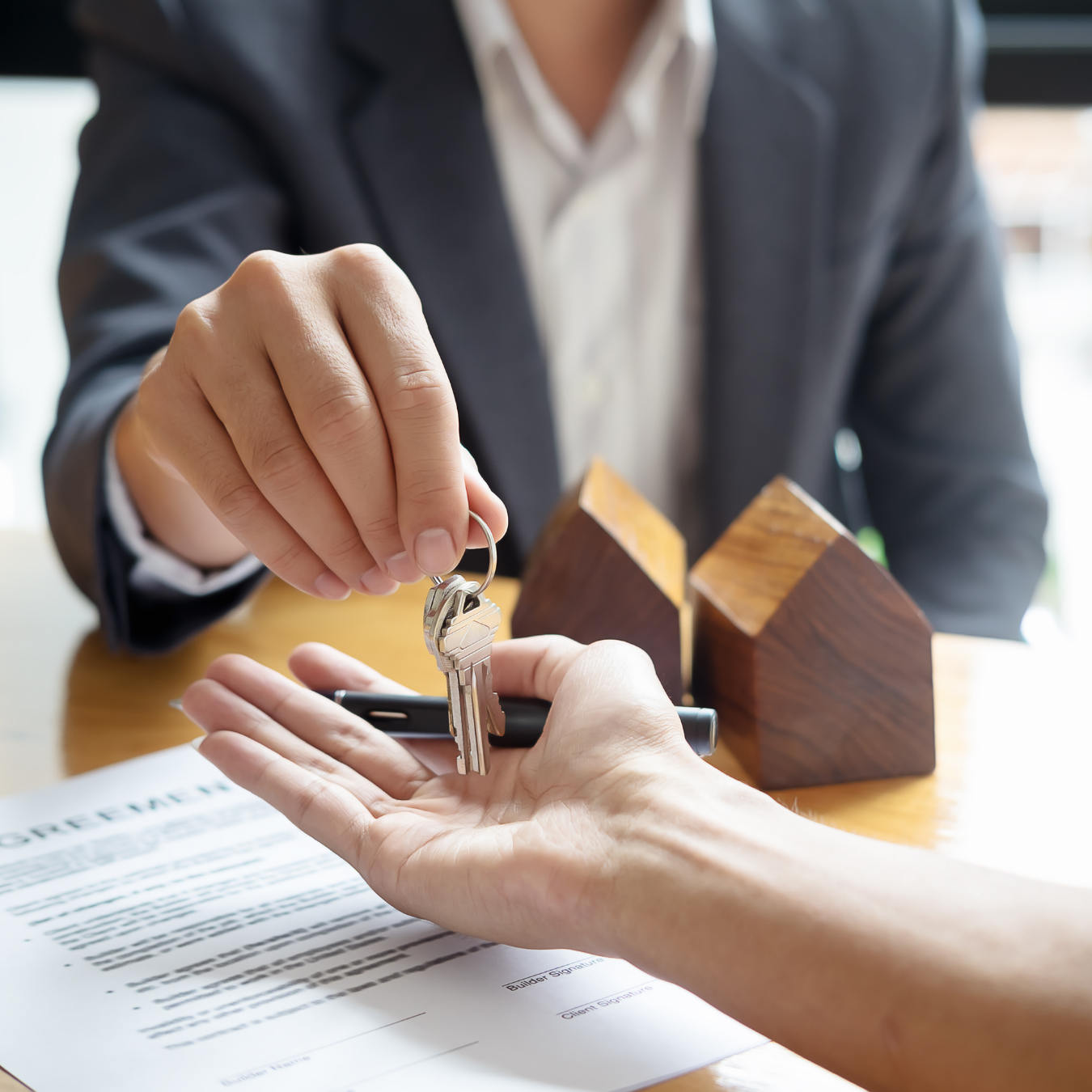 A person handing the keys to a home to another person