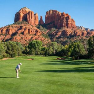 Golf course in Sedona with red rock views and a golfer. A golfer on a course in Sedona with red rock formations in the background.